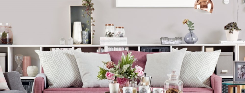Grijze woonkamer met roze bankstel en koperkleurige accenten